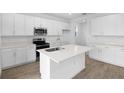 Modern kitchen featuring white cabinets, quartz countertops, stainless steel appliances, and an island with a sink at 5406 Catmint Dr, Lake Hamilton, FL 33851