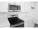 Close up of the stainless steel stove, microwave, and white quartz countertops in the modern kitchen at 5406 Catmint Dr, Lake Hamilton, FL 33851