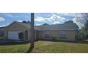 Tan one-story house with a white garage door and landscaping at 2118 Allspice Ave, Orlando, FL 32837