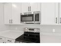 Close-up of stainless steel microwave and oven, and white cabinets in a modern kitchen at 5422 Catmint Dr, Lake Hamilton, FL 33851