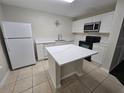 Modern kitchen with white cabinets, white countertops, an island, and stainless steel appliances at 2846 Club Cortile Cir, Kissimmee, FL 34746