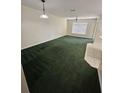 Bright living room with green carpet, a ceiling fan, and a light fixture overhead at 2846 Club Cortile Cir, Kissimmee, FL 34746