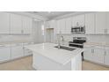 Bright kitchen featuring white cabinets, stainless steel appliances, a large island, and modern finishes at 3716 Deer Ridge Dr, Mount Dora, FL 32757