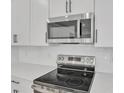 Modern kitchen features stainless steel microwave and electric stovetop with white cabinets and countertops at 3764 Deer Ridge Dr, Mount Dora, FL 32757