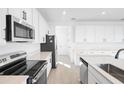 Modern kitchen showcasing white cabinets, stainless steel appliances, an electric range, and a functional island sink at 1485 August Gray Dr, Kissimmee, FL 34744