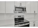 Close-up of kitchen featuring stainless steel appliances, white cabinets, and subway tile backsplash at 3724 Deer Ridge Dr, Mount Dora, FL 32757