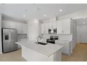 Modern kitchen with stainless steel appliances, white cabinetry, and an island with a sink at 652 Hennepin Loop, Lake Wales, FL 33898
