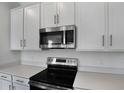 A close-up of a modern black stove, stainless steel microwave, and white cabinets at 652 Hennepin Loop, Lake Wales, FL 33898