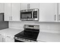 Close up on new stainless steel oven range and microwave with white countertops and cabinetry at 656 Hennepin Loop, Lake Wales, FL 33898