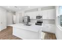 Bright kitchen with stainless steel appliances, white cabinets, and a large center island at 656 Hennepin Loop, Lake Wales, FL 33898