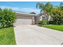 Traditional home featuring a two-car garage and driveway with beautiful mature landscaping at 1569 Thetford Cir, Orlando, FL 32824