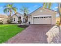 Brick paver driveway and landscaping leading to a tan house at 3634 Northwoods Dr, Kissimmee, FL 34746