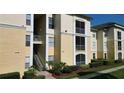 A daytime shot shows an exterior view of the light yellow apartment building with its concrete stairs at 8910 Legacy Ct # 206, Kissimmee, FL 34747