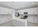 Modern kitchen features white cabinetry, a center island, quartz countertops, and stainless steel appliances at 1488 August Gray Dr, Kissimmee, FL 34744