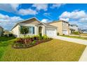 Well-kept single-story house with vibrant landscaping, a driveway, and an attached two-car garage at 527 Noble Ave, Davenport, FL 33837