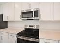 Close up of kitchen with stainless steel oven, microwave, white cabinets and quartz countertops at 1698 Sugarbelle Cir, Mascotte, FL 34753
