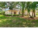 Inviting single-Gathering home featuring lush landscaping, mature trees, and a cozy front porch at 753 Largo Pass, Poinciana, FL 34759