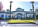 Exterior view of the community clubhouse, surrounded by lush landscaping and palm trees at 8830 Dunes Ct # 12 207, Kissimmee, FL 34747