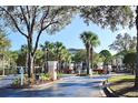 View of community entrance with gated access for residents, palm trees, and landscaping at 8830 Dunes Ct # 12 207, Kissimmee, FL 34747