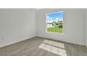 Bright bedroom with wood-look tile floors and a large window showcasing a lush green yard at 314 Dagama Ct, Kissimmee, FL 34758
