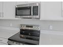 Close-up showcasing stainless steel microwave and stove with white cabinetry at 5414 Catmint Dr, Lake Hamilton, FL 33851