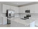 Bright, open kitchen featuring a large island, stainless steel appliances, and white cabinetry at 5414 Catmint Dr, Lake Hamilton, FL 33851