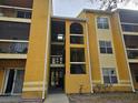 Exterior of yellow two-story apartment complex showing stairways and walkways at 5267 Images Cir # 303, Kissimmee, FL 34746