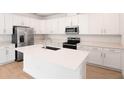 Modern kitchen featuring white cabinetry, stainless steel appliances, and a large island at 1742 Carnelian St, Deland, FL 32720