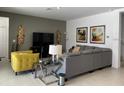 Spacious living room with gray sectional sofa, yellow accent chair, and large TV at 3850 Oakville Ave, Kissimmee, FL 34741