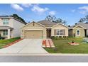 Tan house with brown shutters, landscaped yard, and a paved driveway at 965 Shady Tree Ln, Davenport, FL 33897