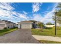 One-story house featuring a gray exterior, paver driveway, and a well-maintained lawn at 113 Promenade Ct, Auburndale, FL 33823