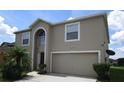 Two-story house with tan exterior, landscaping, and a two-car garage at 137 Milestone Dr, Haines City, FL 33844