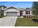 Charming home featuring a manicured lawn, stone accents, and a two-car garage at 1695 Sugarbelle Cir, Mascotte, FL 34753