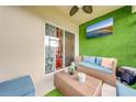 Relaxing patio with artificial turf, wicker furniture, and a large TV at 1242 Iguana Loop, Davenport, FL 33897
