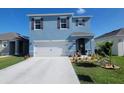 Two-story home with a manicured lawn and garden, two-car garage, and blue exterior at 2459 Taloncrest Ct, Eagle Lake, FL 33839