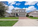 Two-story house with gray siding, brick driveway, and landscaped lawn at 437 Seattle Slew Dr, Davenport, FL 33837