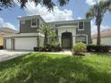 Beautiful two-story home featuring a three car garage, lush lawn, and tropical landscaping at 8557 La Isla Dr, Kissimmee, FL 34747
