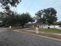 Gray house with black door, mature landscaping, and street view at 1504 Hummingbird Ln, Lakeland, FL 33801