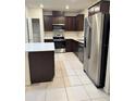 Modern kitchen featuring dark cabinetry, stainless steel appliances, and a large island at 1655 Aspen Ave, Davenport, FL 33837