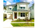 Two-story light green house with a red door, attached garage, and well-manicured lawn at 1829 Tropical Palms Cir Cir, Kissimmee, FL 34747