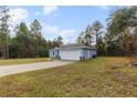 House exterior showcasing a spacious driveway and wooded surroundings at 832 Marion Oaks Mnr, Ocala, FL 34473