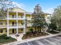 Three-story yellow building with balconies, landscaping, and parking at 312 Lucaya Loop # B5/U312, Davenport, FL 33897