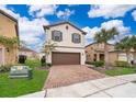 Two-story house with brown garage door and brick driveway, surrounded by palm trees at 5505 Misty Oak Cir, Davenport, FL 33837