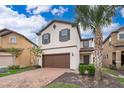 Two-story house with brown garage door and brick driveway, surrounded by palm trees at 5505 Misty Oak Cir, Davenport, FL 33837