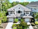 Aerial view of luxury home featuring manicured landscaping, brick driveway, and a beautiful tile roof at 8162 Valhalla Ter, Reunion, FL 34747
