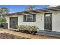 House's front entrance with gray door and landscaping at 110 E Palmetto Ave, Howey In The Hills, FL 34737