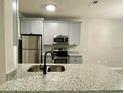 Modern kitchen with gray cabinets, granite countertops, stainless steel appliances, and a breakfast bar at 3011 Hemingway Cir # 3011, Haines City, FL 33844