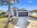 House exterior with gray walls, dark brown garage door, and landscaping at 370 Henley Cir, Davenport, FL 33896