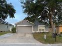 Charming single-story home featuring a gray exterior, well-manicured lawn, and a convenient two-car garage at 435 Madina Cir, Davenport, FL 33837