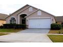 Tan house with white garage door and landscaping at 1068 Lake Berkley Dr, Kissimmee, FL 34746